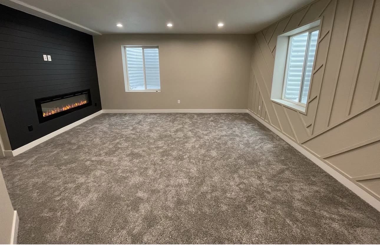 Finished basement with an electric fireplace on a shiplap wall